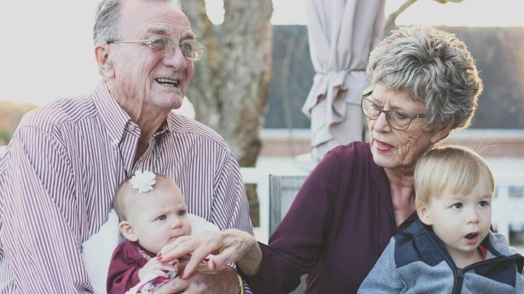 Grandparents spending joyful moments with their grandchildren in an outdoor setting, captured candidly.