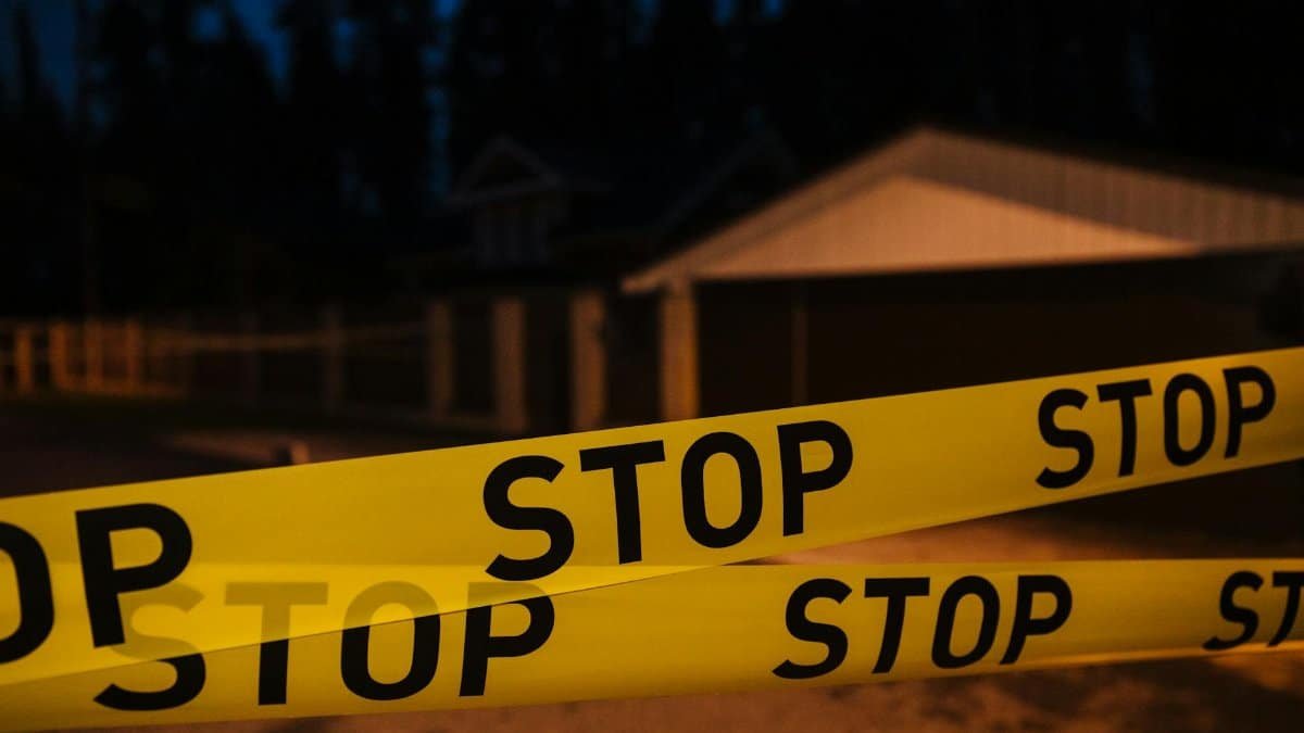 Yellow stop tape blocking a residential street at night, creating a restricted area.