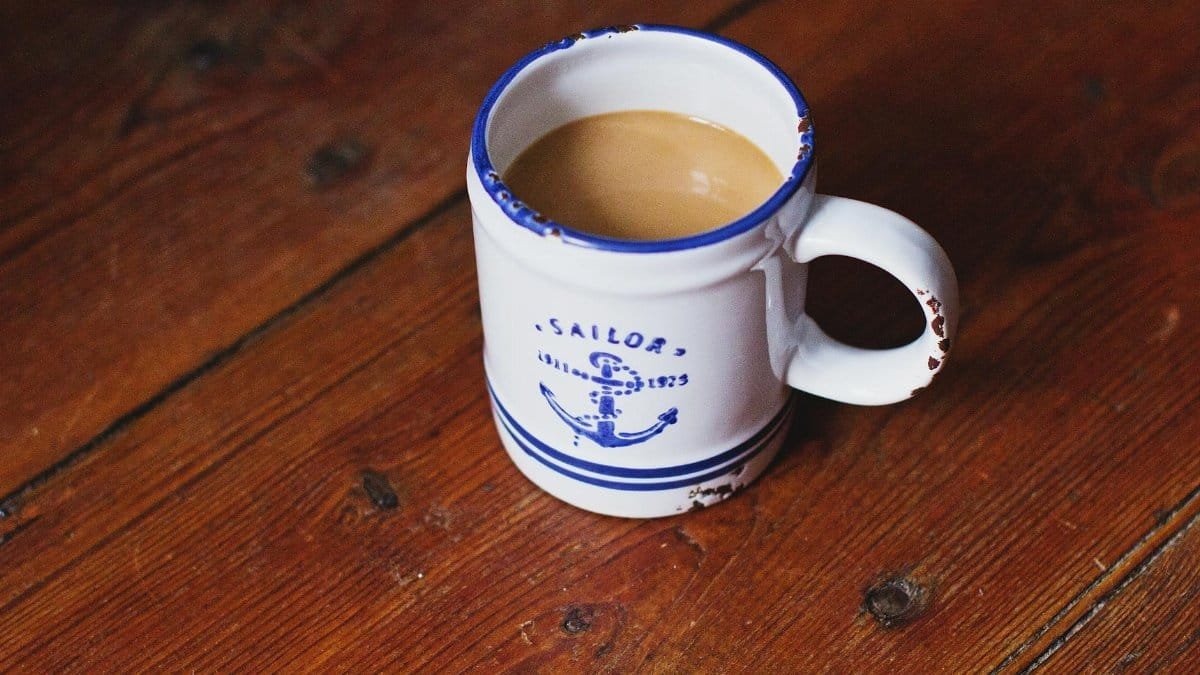 Vintage sailor-themed coffee mug filled with hot brew on a rustic wooden table, evoking a warm and cozy feeling.