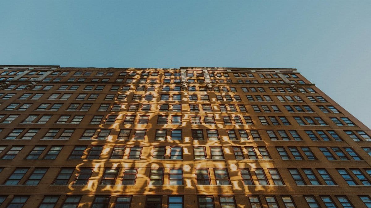 A high-rise building facade adorned with unique light reflections under a clear blue sky.