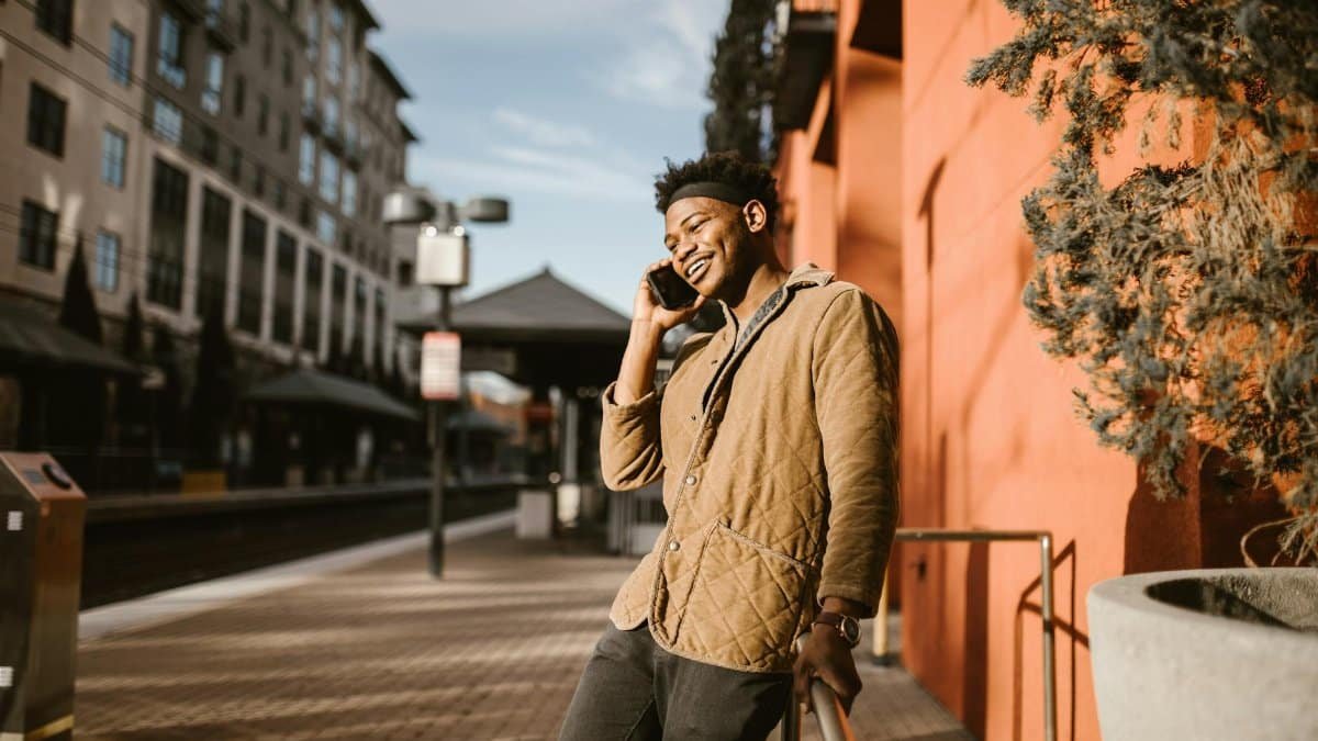Smiling young man in a city setting talking on his phone outdoors.