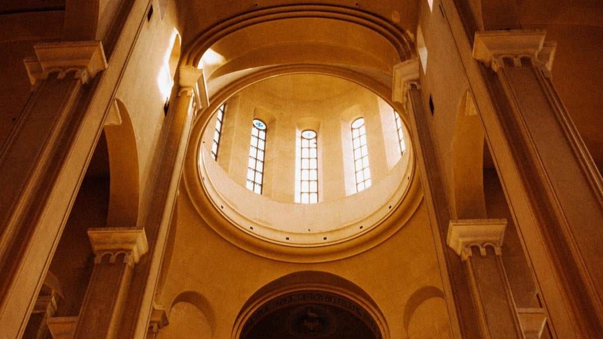 Majestic architectural interior of a cathedral in Tbilisi, Georgia, showcasing elegant arches and stained glass windows.