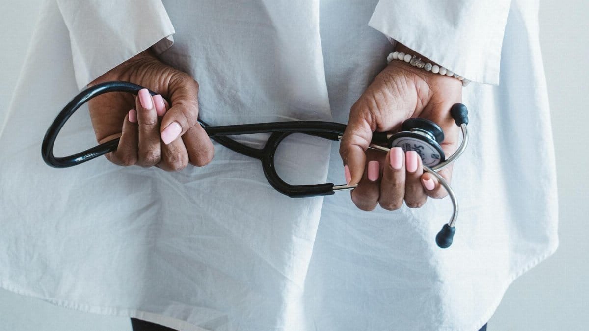 A medical professional holding a stethoscope in a clinical setting.