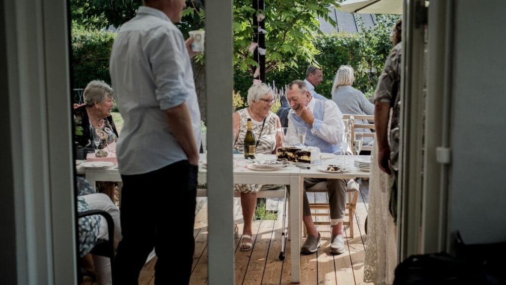 A relaxed outdoor gathering with friends enjoying food and drinks in a garden setting.