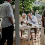 A relaxed outdoor gathering with friends enjoying food and drinks in a garden setting.