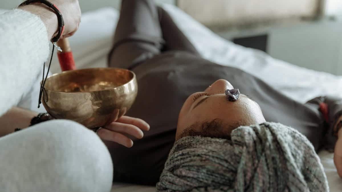 A serene relaxation therapy session with a Tibetan singing bowl and crystal on forehead, promoting spiritual healing.