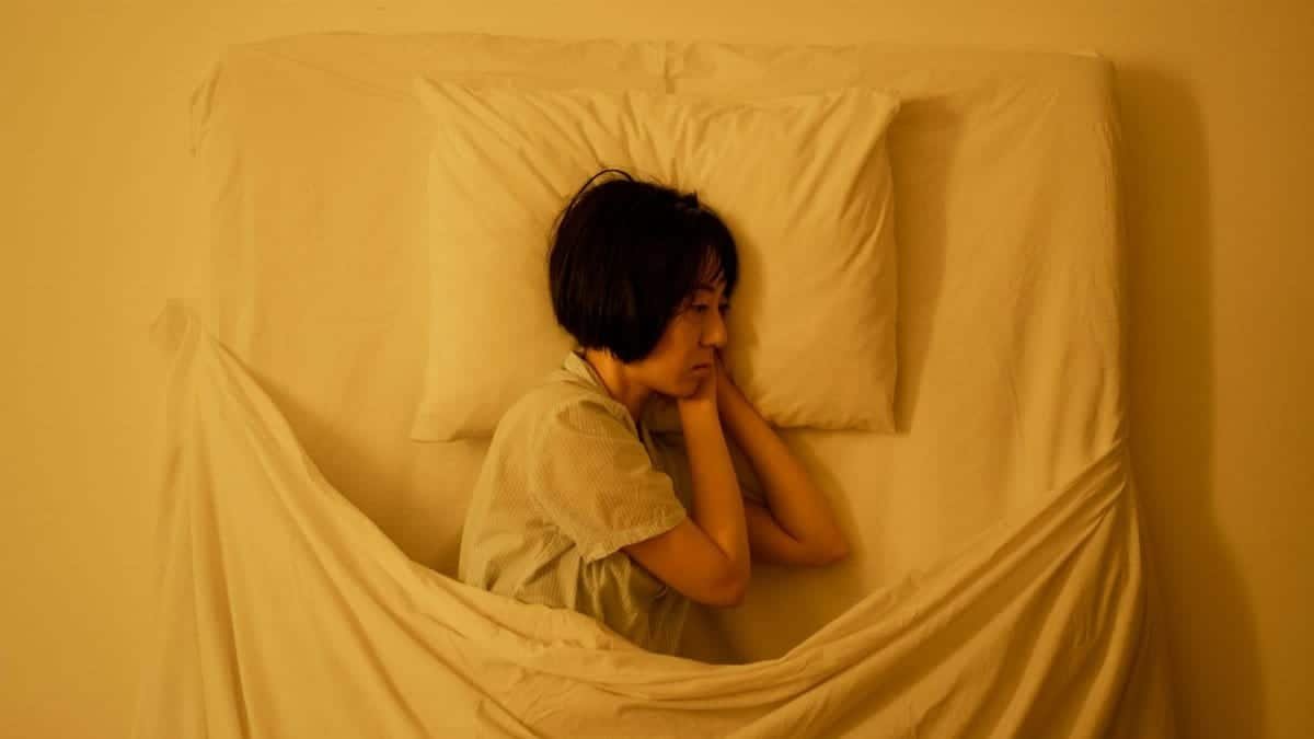 A woman lies in bed, reflecting deep emotions related to mental health issues.