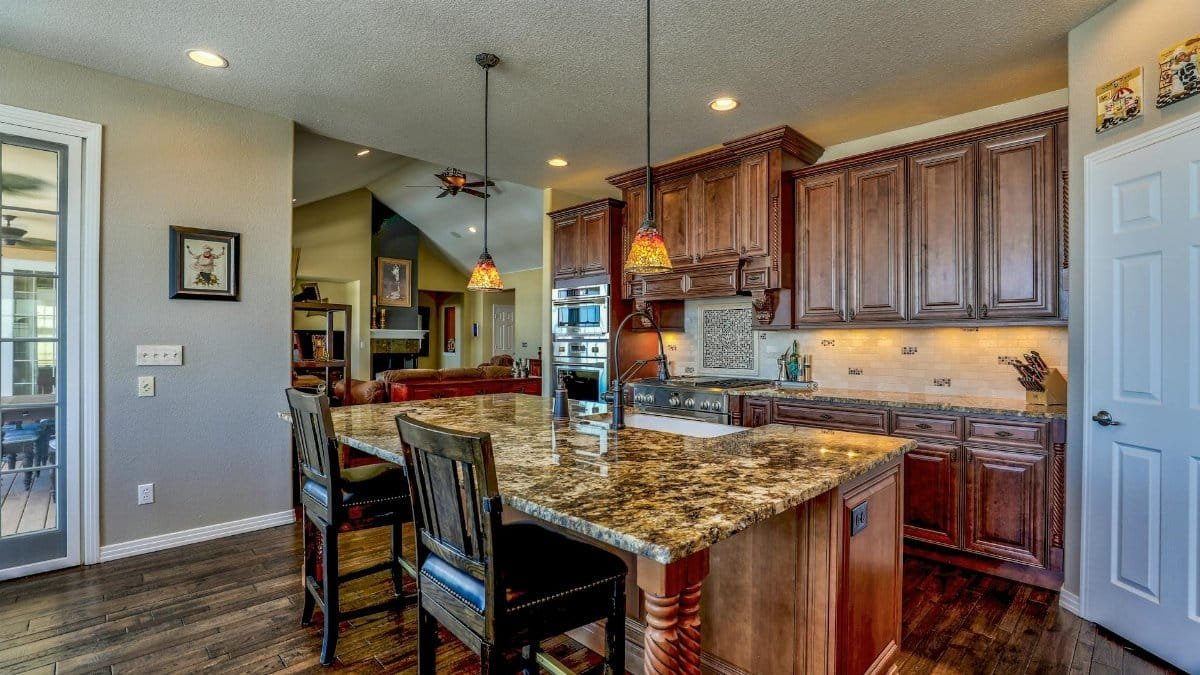 A stylish kitchen featuring a granite island, wooden cabinets, and modern appliances. Perfect blend of rustic and contemporary design.