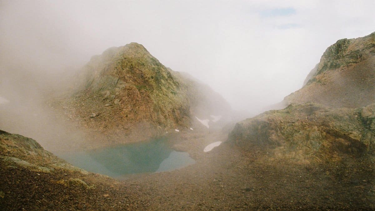 A serene misty mountain scene with a tranquil lake surrounded by rocky terrain in Spain.