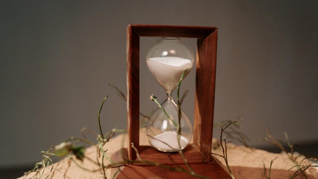 Close-up of a wooden hourglass with sand flowing, symbolizing time and nature.