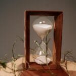 Close-up of a wooden hourglass with sand flowing, symbolizing time and nature.