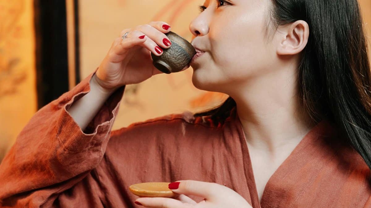 A serene moment of a woman savoring tea during a traditional ceremony in an intimate setting.