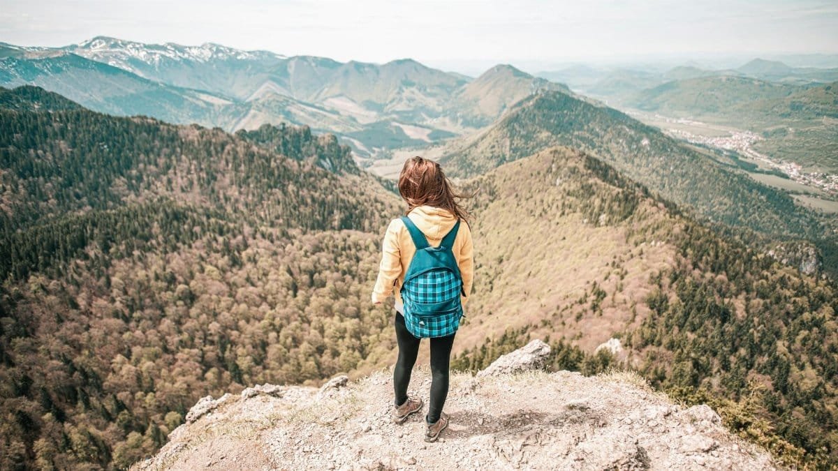 Woman overlooks Malá Fatra mountain range in Slovakia. Captivating scenic view from peak.