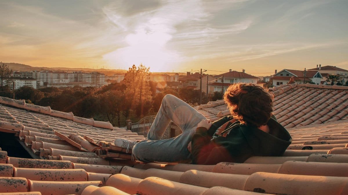 A person relaxing on a rooftop, enjoying a serene sunset view over the cityscape.