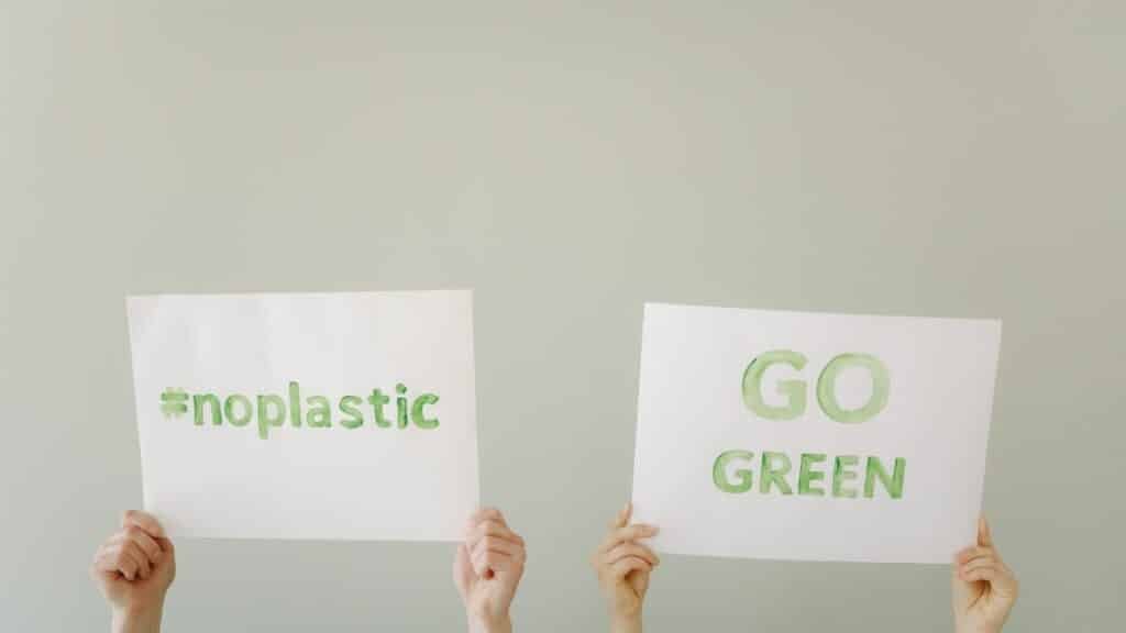 Hands holding eco-friendly signs advocating 'No Plastic' and 'Go Green'. Environmental awareness concept.