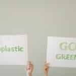 Hands holding eco-friendly signs advocating 'No Plastic' and 'Go Green'. Environmental awareness concept.