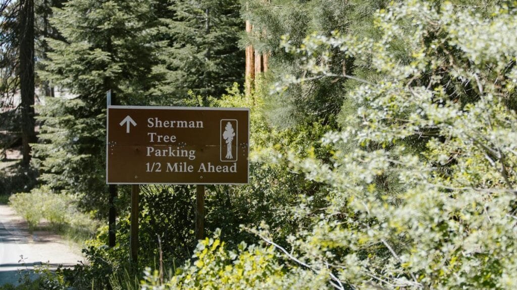 Sign indicating Sherman Tree parking is half a mile ahead in Sequoia National Park.