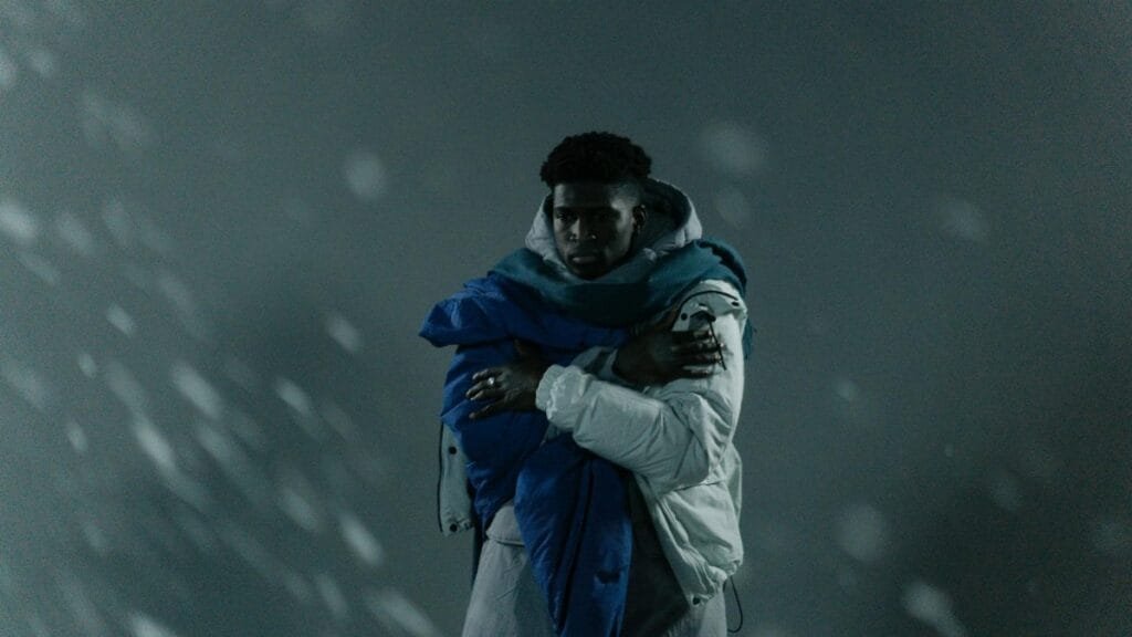 A man wrapped in a warm jacket and scarf braves the cold winter snow.