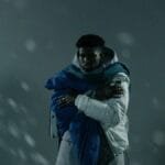 A man wrapped in a warm jacket and scarf braves the cold winter snow.