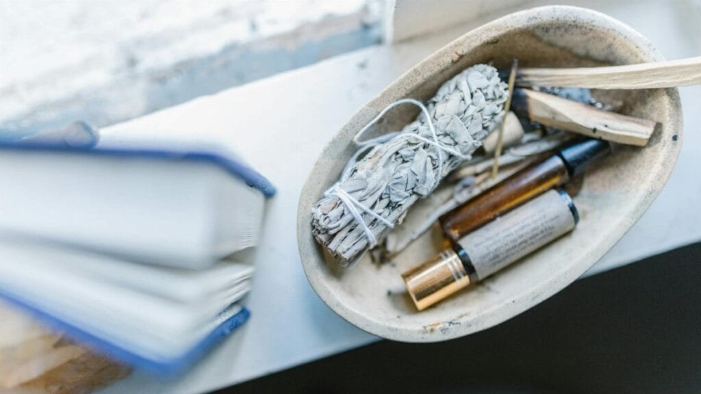 A calming arrangement of healing crystals, sage, and essential oils on a windowsill for spiritual rituals.
