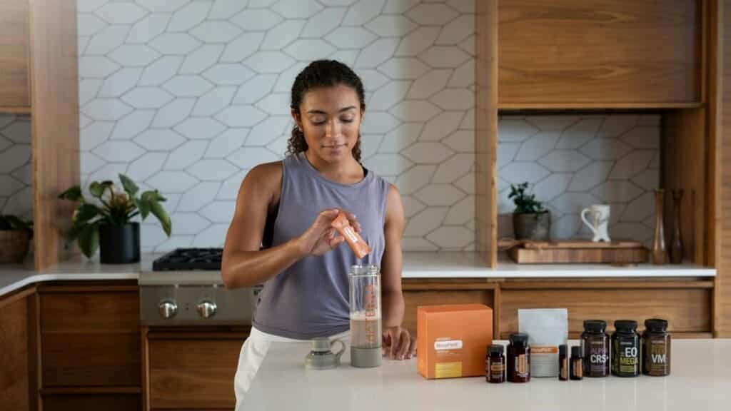 A woman uses essential oils and supplements in a contemporary kitchen for wellness.