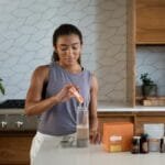 A woman uses essential oils and supplements in a contemporary kitchen for wellness.