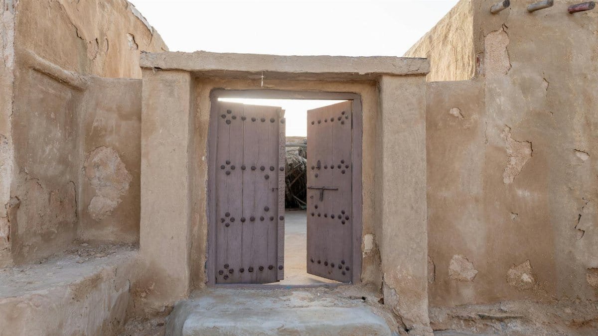 A rustic desert gateway opening into an old town courtyard, reflecting traditional architecture.