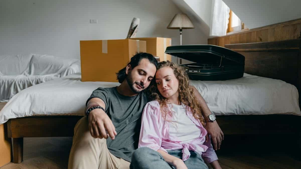 A couple cuddling and relaxing together on moving day with boxes around them.