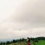 A man in a checkered shirt enjoys a quiet moment in the scenic mountains of Indian Hills, Colorado.