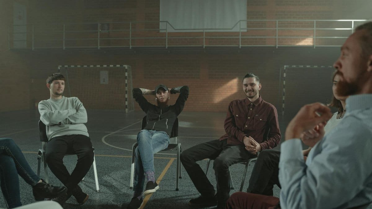 A group of adults engaging in a therapy session in a spacious gymnasium setting.