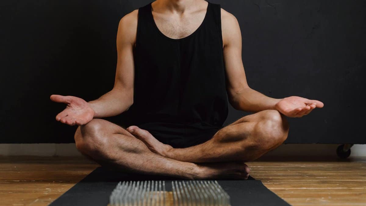 Adult male practicing meditation indoors with a focus on a nails board, promoting mindfulness and calmness.