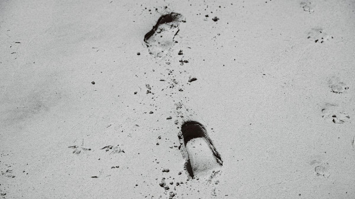 Black and white image of footprints in the sand, showcasing solitude and journey.