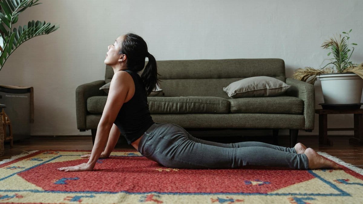 Woman doing yoga cobra pose in a tranquil indoor setting on a vibrant carpet.