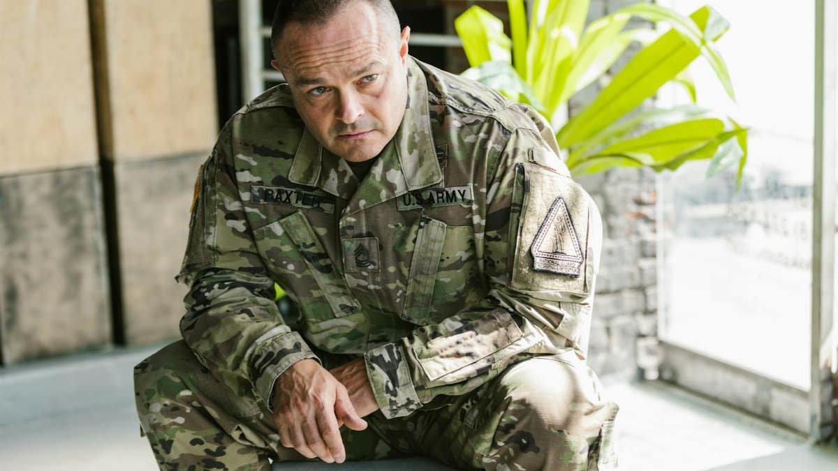 Focused army soldier sitting indoors in military uniform.