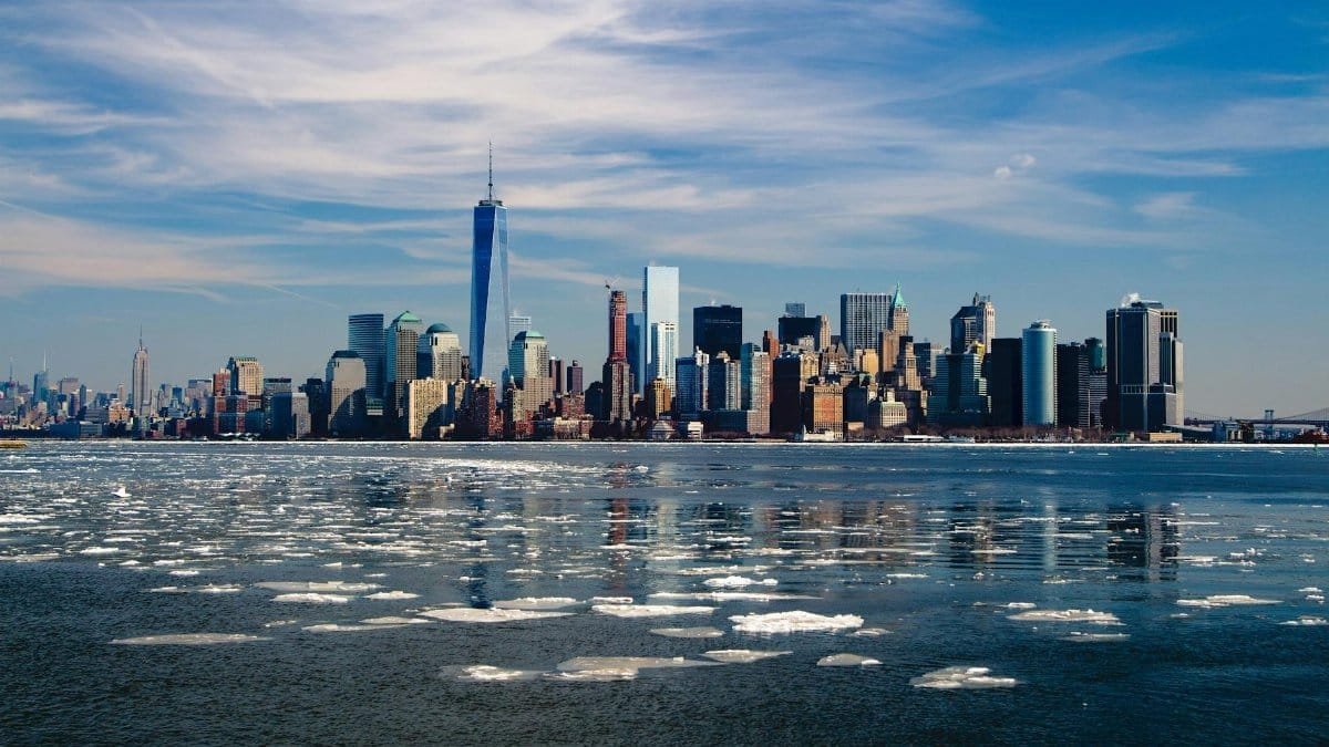 A stunning winter morning captures New York City skyline with icy waters in the foreground.