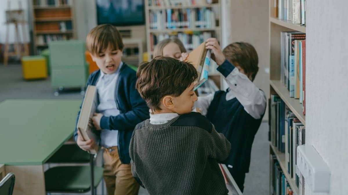 Children engaging in a playful conflict in a school library setting.