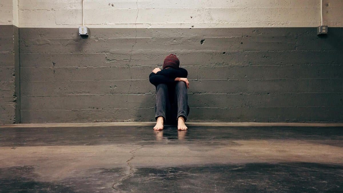 A person sitting alone in a corner, evoking themes of solitude and emotion.