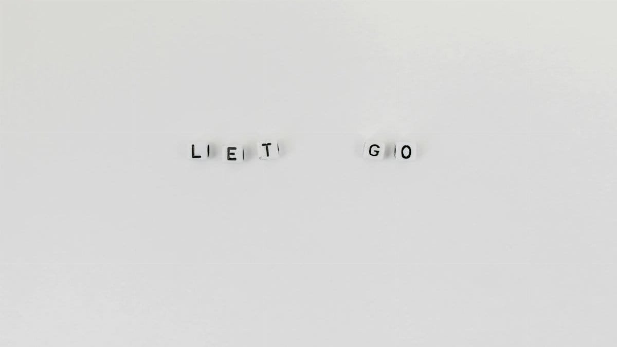 Minimalist composition featuring 'Let Go' spelled with letter dice on a clean white background.