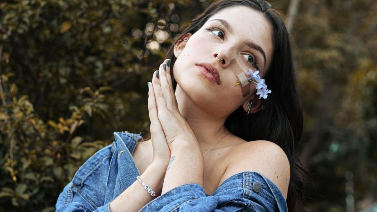 A captivating portrait of a woman with flowers and a band-aid, wearing a denim jacket outdoors.