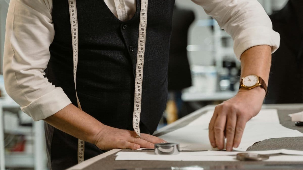 An experienced tailor measuring fabric on a workspace, showcasing precision and craftsmanship.