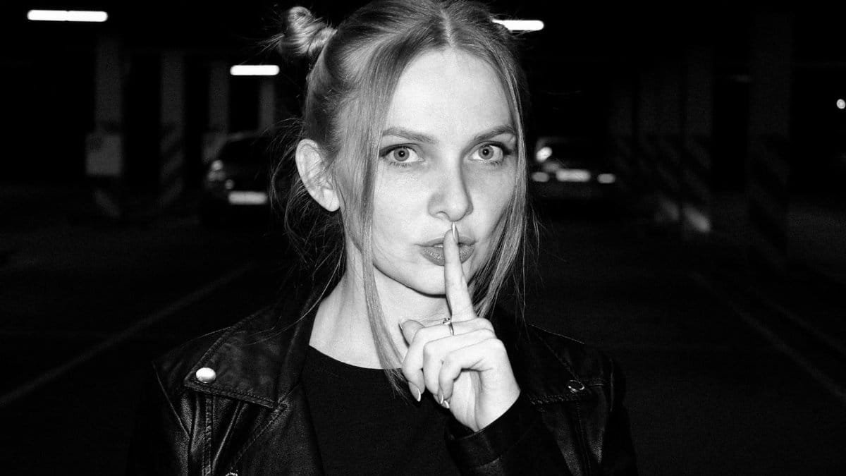 Black and white portrait of a woman making a quiet gesture in an urban garage.