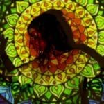 A vibrant mandala pattern projected onto a woman's silhouette, creating an artistic, esoteric atmosphere.