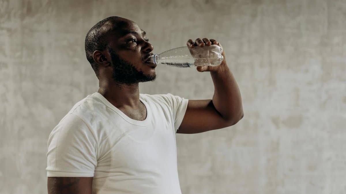 Healthy living concept: Man staying hydrated with water. Indoors, fitness focus.