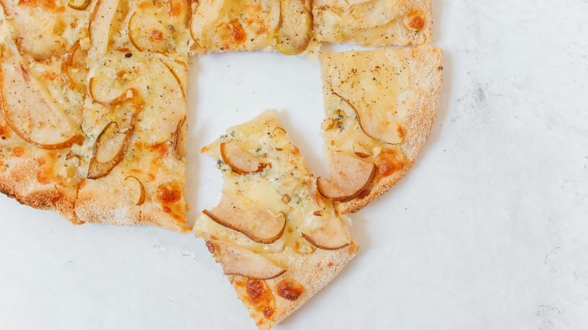 Delicious gourmet pizza topped with pear slices and Gorgonzola cheese on a white background.