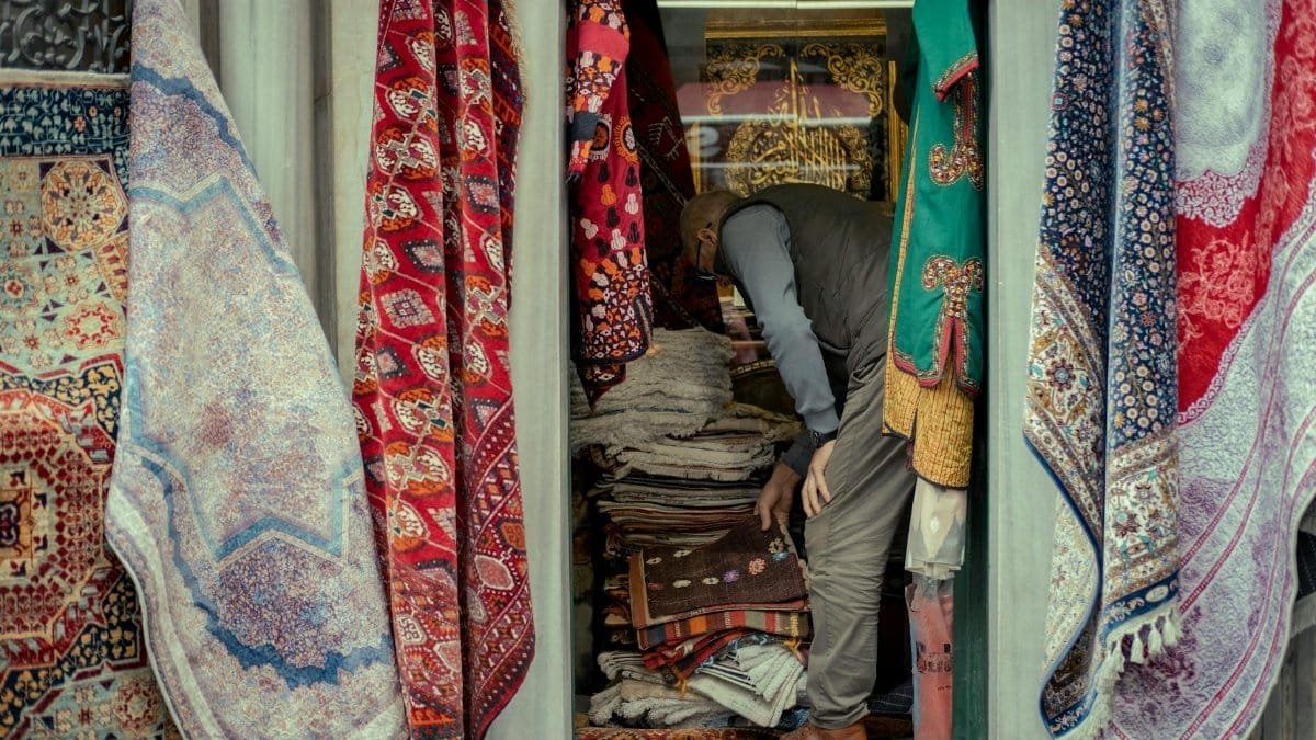 Vibrant market stall showcasing a variety of colorful traditional rugs and carpets, capturing local commerce.