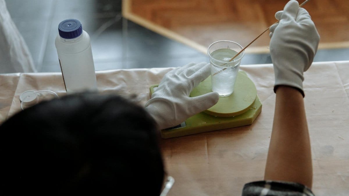 Close-up of a man mixing resin with gloves in an indoor workshop setting.