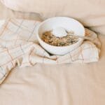 A bowl of granola with yogurt on a bed, exuding a cozy morning ambiance.