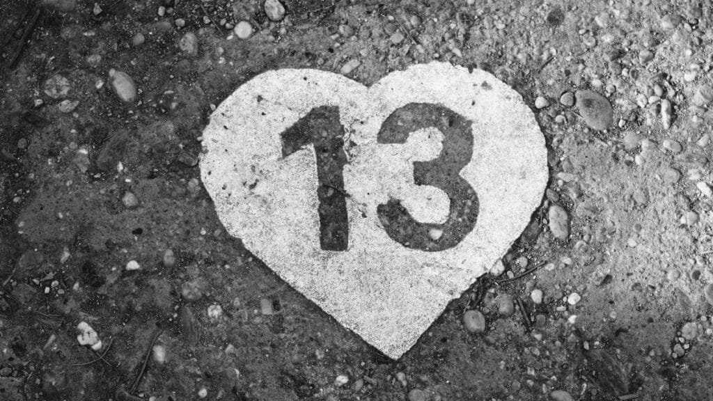 Black and white photo of a heart-shaped number 13 on a pebbled ground in Budapest.