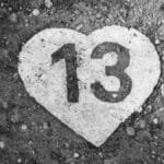 Black and white photo of a heart-shaped number 13 on a pebbled ground in Budapest.