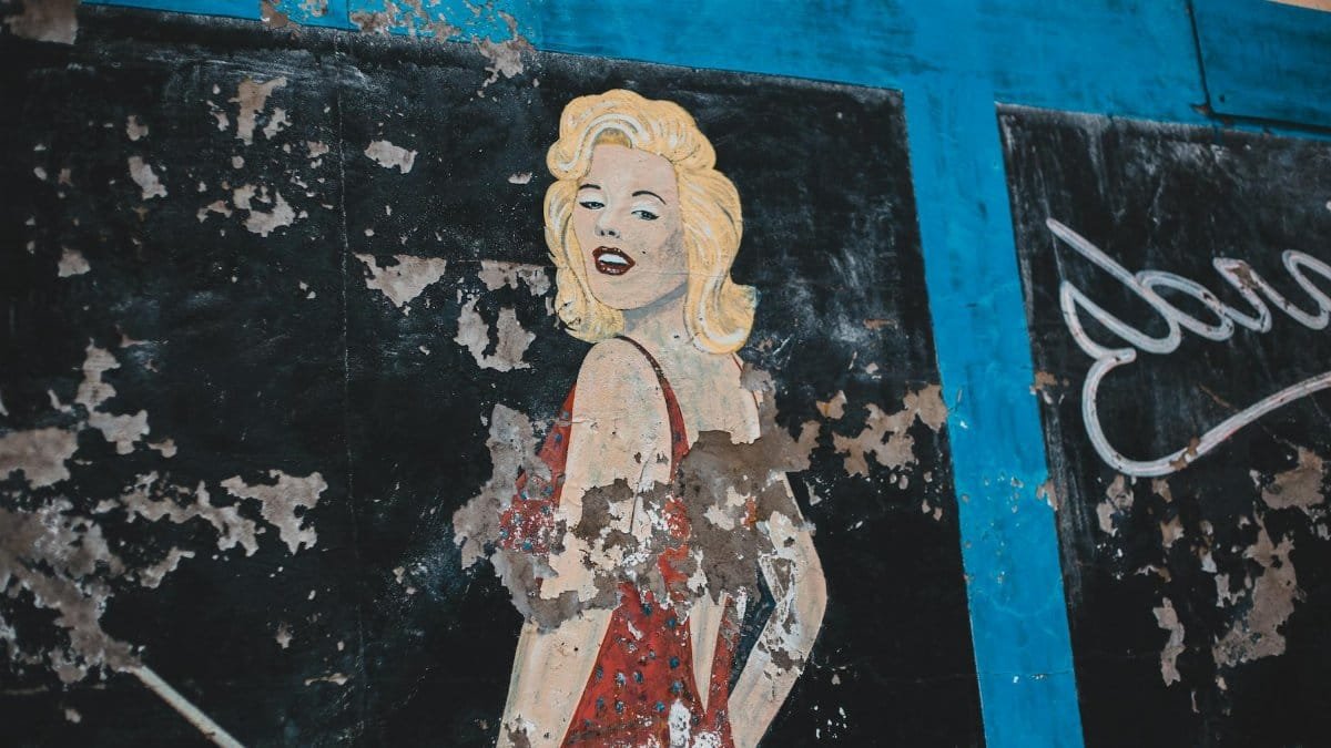 Colorful graffiti art of a glamorous vintage actress on a weathered wall, showcasing urban creativity.